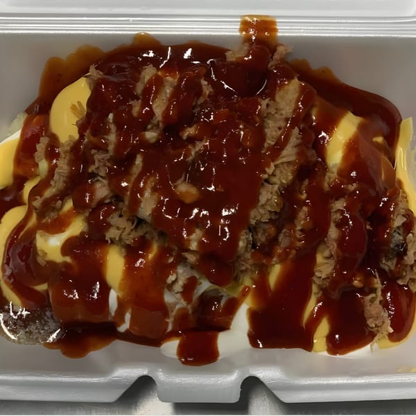 Bama Boys BBQ loaded baked potato with pulled pork, cheese sauce, and barbecue sauce.