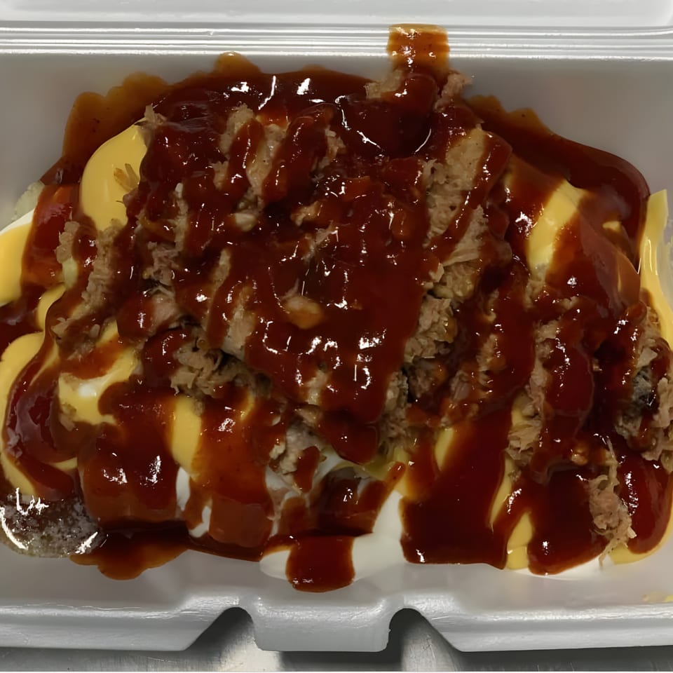 Bama Boys BBQ loaded baked potato with pulled pork, cheese sauce, and barbecue sauce.