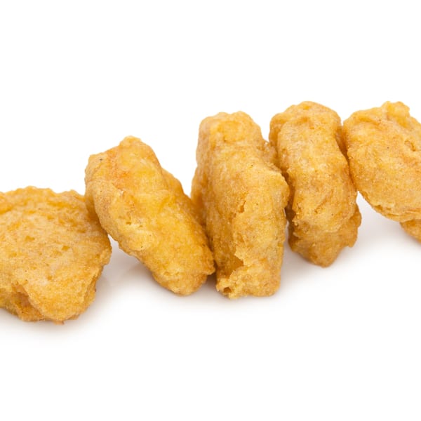 Golden-brown, crispy chicken nuggets from Bama Boys BBQ arranged in a line on a white background.