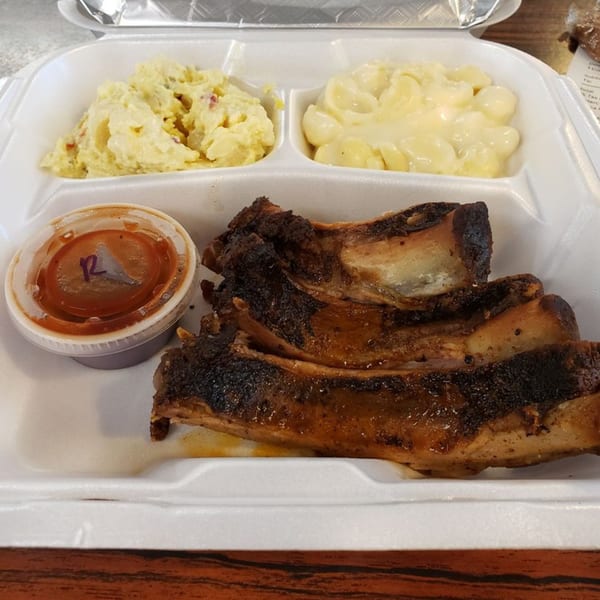 Bama Boys BBQ ribs with potato salad, mac and cheese, and a side of BBQ sauce.